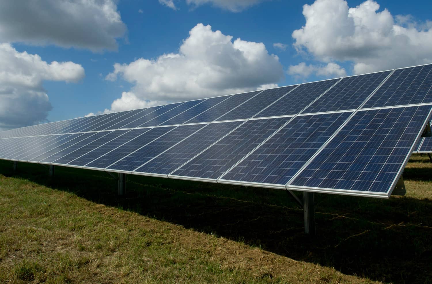 Abbildung einer Solaranlage auf einem grünen Feld mit blauem Himmel und weißen Wolken.