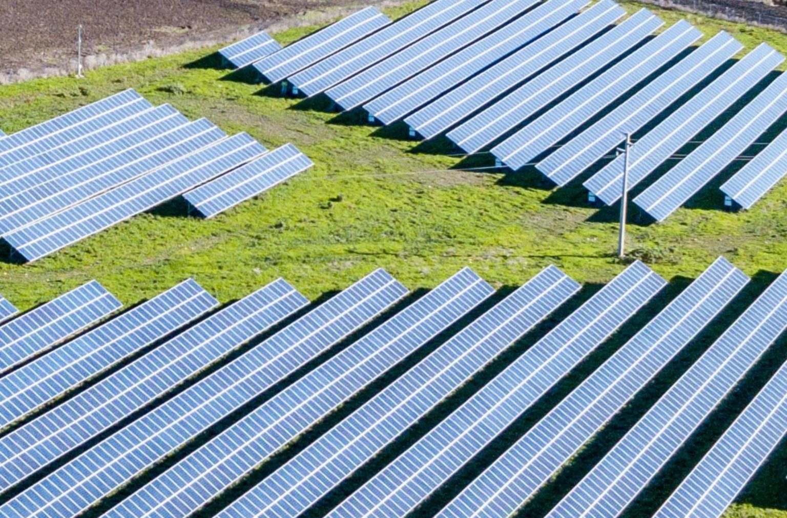 Luftaufnahme eines Solarparks mit einzelnen Freiflächen für PV-Investments